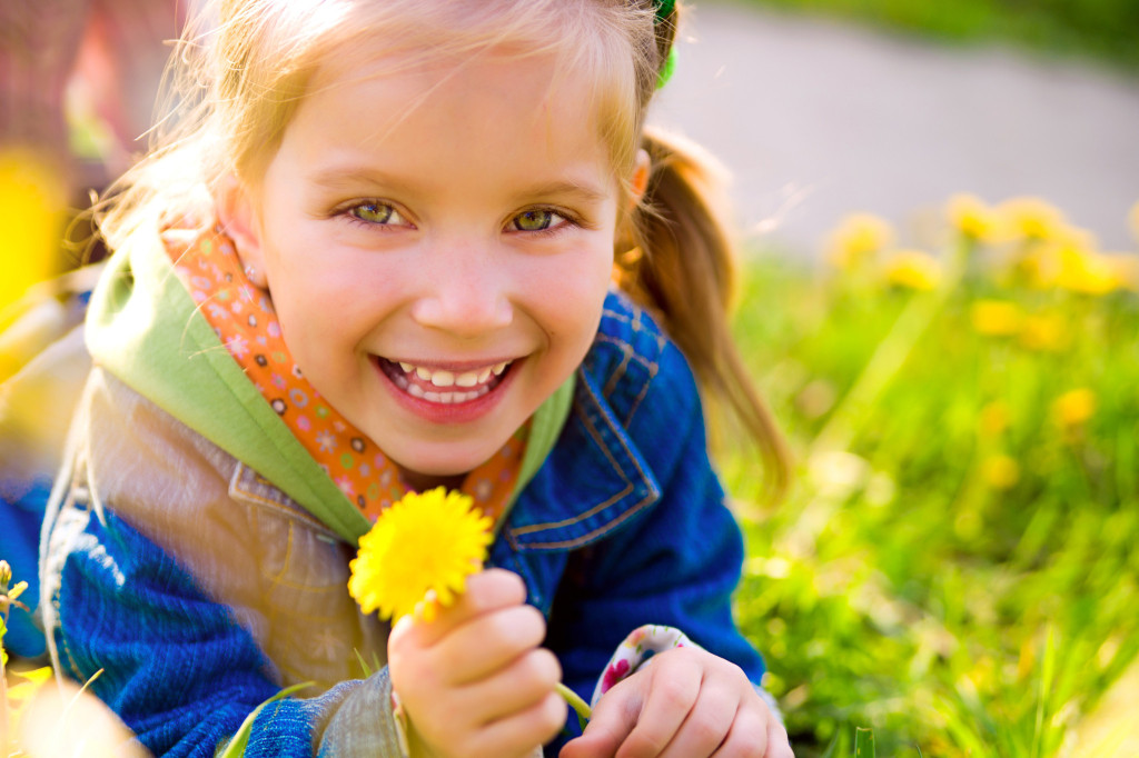 Young girl holding a flower and smiling.